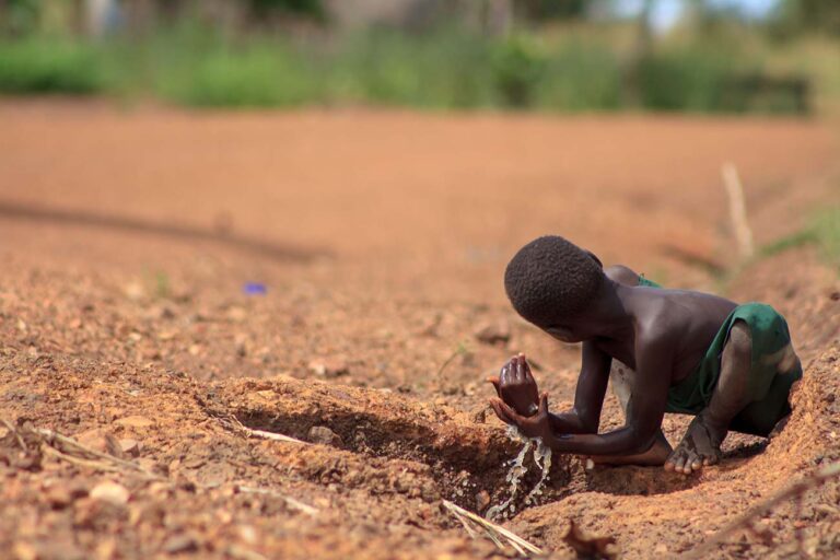 A-refugee-child-from-south-sudan-washes-his-hands-in-a-puddle-of-water-by-the-roadside-in-bidibidi-refugee-campYumbeUganda